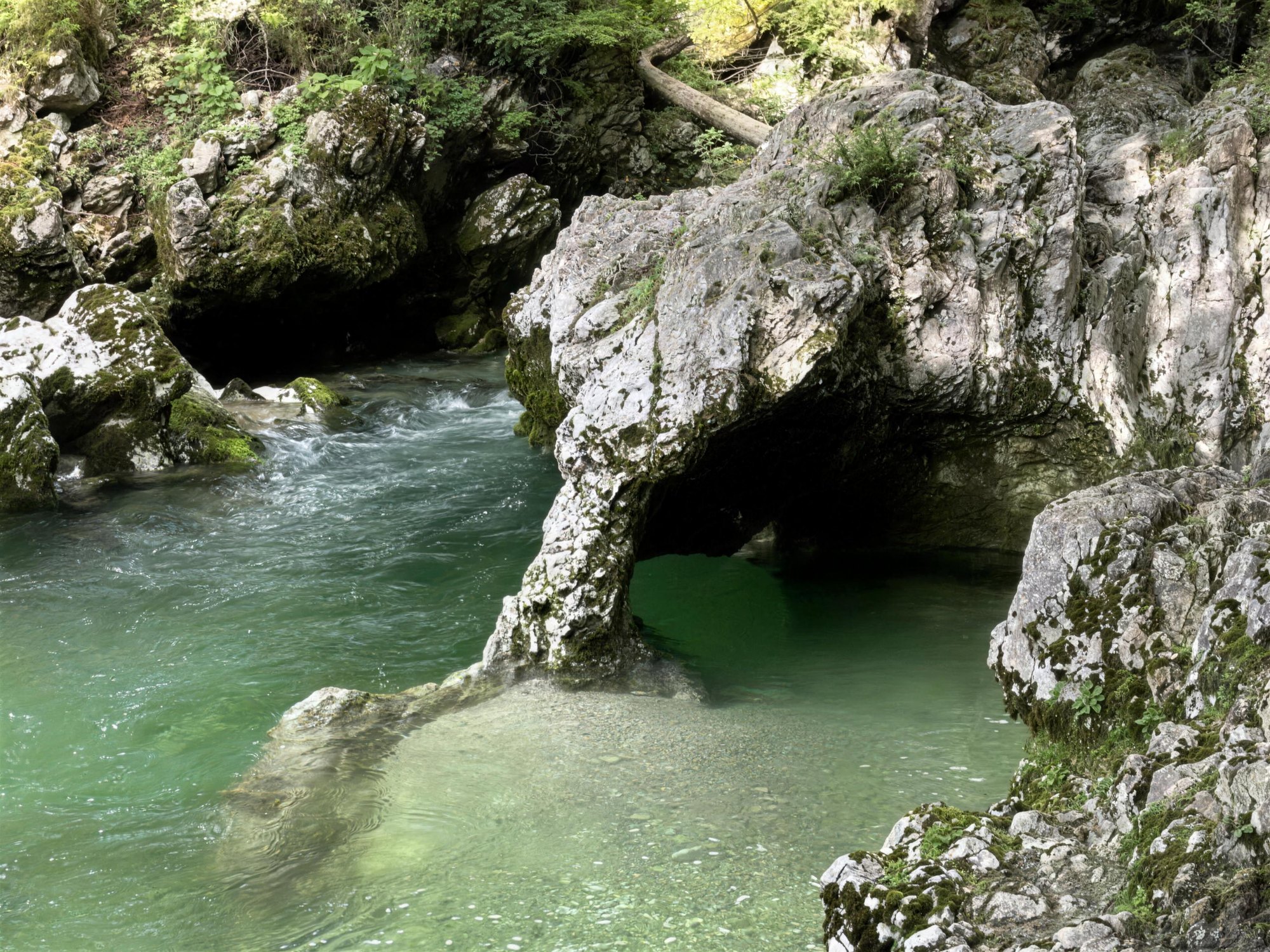 Clear emerald pools and a natural rock arch in a limestone gorge near Lake Bohinj